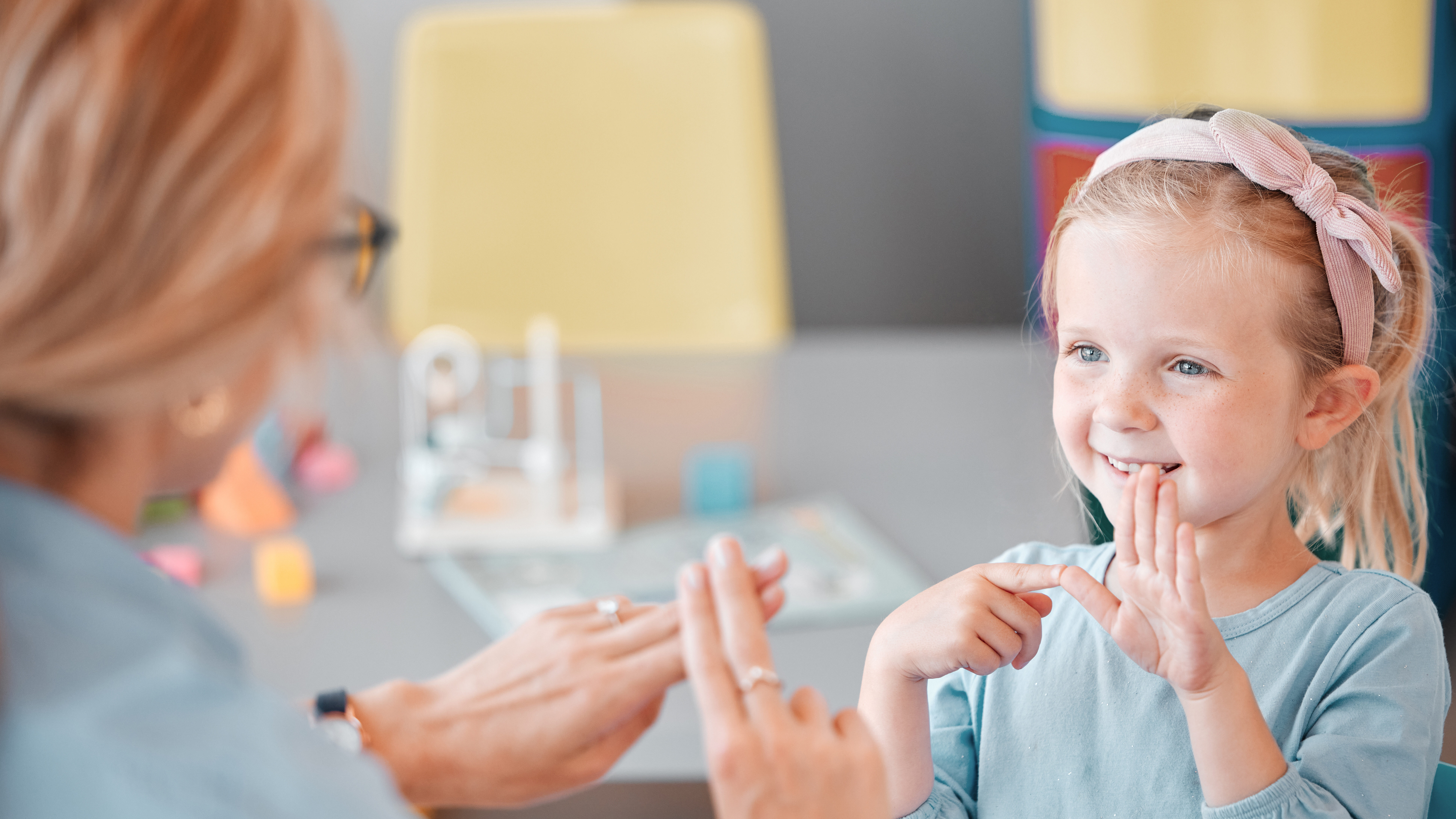 Adorable petite fille caucasienne souriante debout et utilisant le langage des signes pour communiquer avec l'enfant